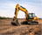 Yellow excavator on a construction site with a clear sky.